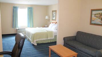 A hotel room with a bed, a sofa, a wooden table, and a chair.