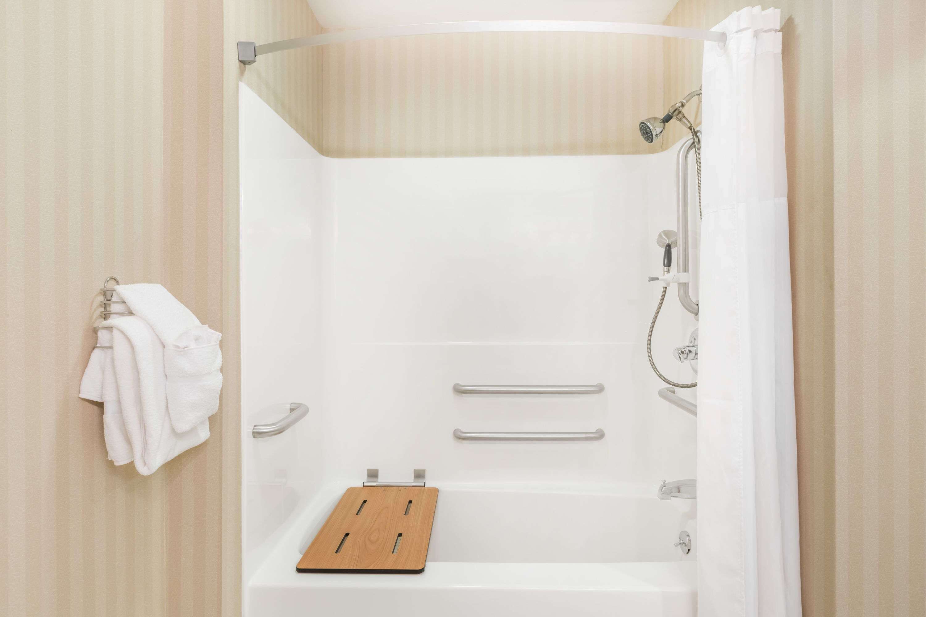 Un espace douche moderne avec un plateau en bois, des poignées en métal et une pomme de douche.