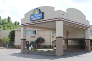 Un bâtiment Days Inn & Suites doté d’un parking couvert, d’un drapeau américain et d’une entrée agrémentée de jardins.