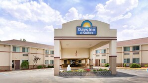 Een Days Inn & Suites met een centrale ingang, een Amerikaanse vlag en een parkeerplaats.
