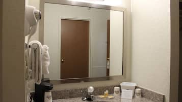 A hotel bathroom with a sink, mirror, towel rack, and toiletries.