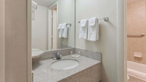 A bathroom with a granite countertop sink, a mirror, and two towel racks with white towels.