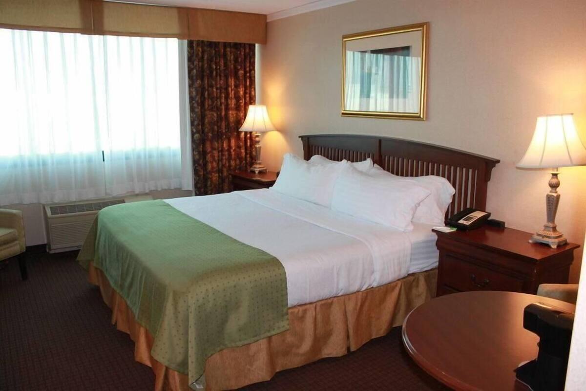 A hotel room with a bed, two bedside tables with lamps, a chair, and a small table.
