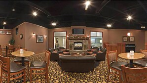 A cozy lounge area with a fireplace, comfortable seating, and a patterned carpet. - Days Inn by Wyndham Warren (Warren)