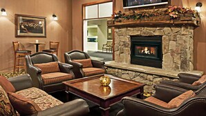 A cozy living room with leather sofas, a stone fireplace, and a flat-screen TV mounted above the fireplace.