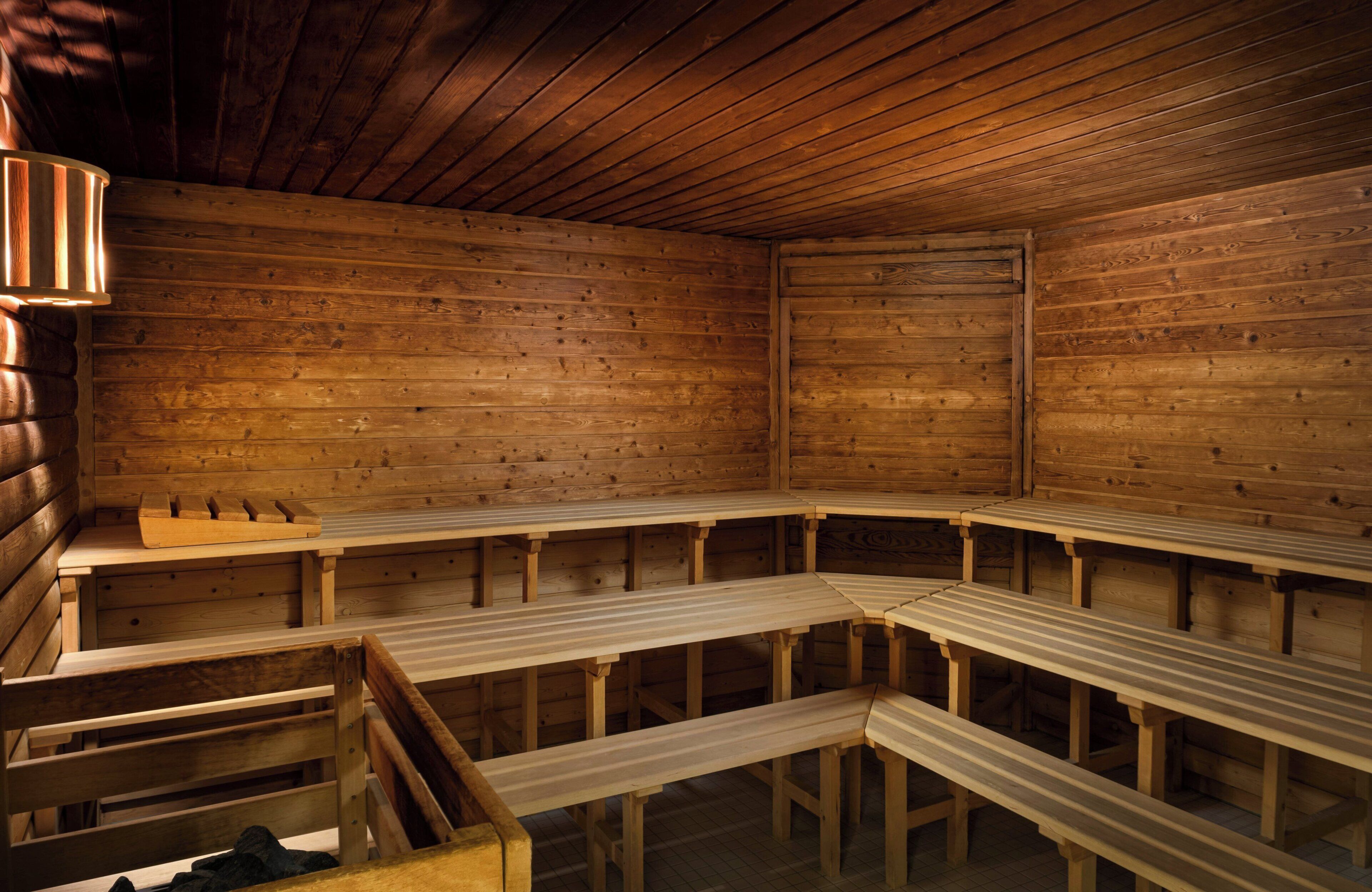 Una sauna con bancos de madera y un banco con respaldo.