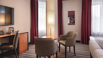 Una habitación de hotel con una cama, un escritorio con una computadora portátil, dos sillas, una lámpara y un televisor.