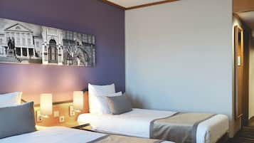 A hotel room with two beds, a large painting on the wall, and a hallway leading to another room.
