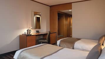 Une chambre d’hôtel avec deux lits, un bureau avec une chaise, un miroir et une armoire.