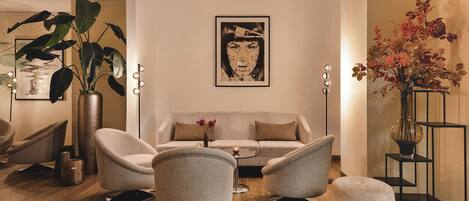 Una sala de estar moderna con un sofá, dos sillones, una mesa de centro y una planta decorativa.