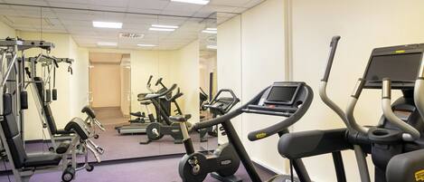 Une salle de sport équipée de tapis de course, de vélos elliptiques et de matériel de musculation.