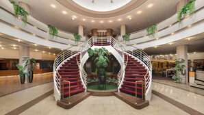 A spacious lobby with a central spiral staircase, multiple levels, and indoor plants. - Leonardo Hotel Weimar (Weimar)