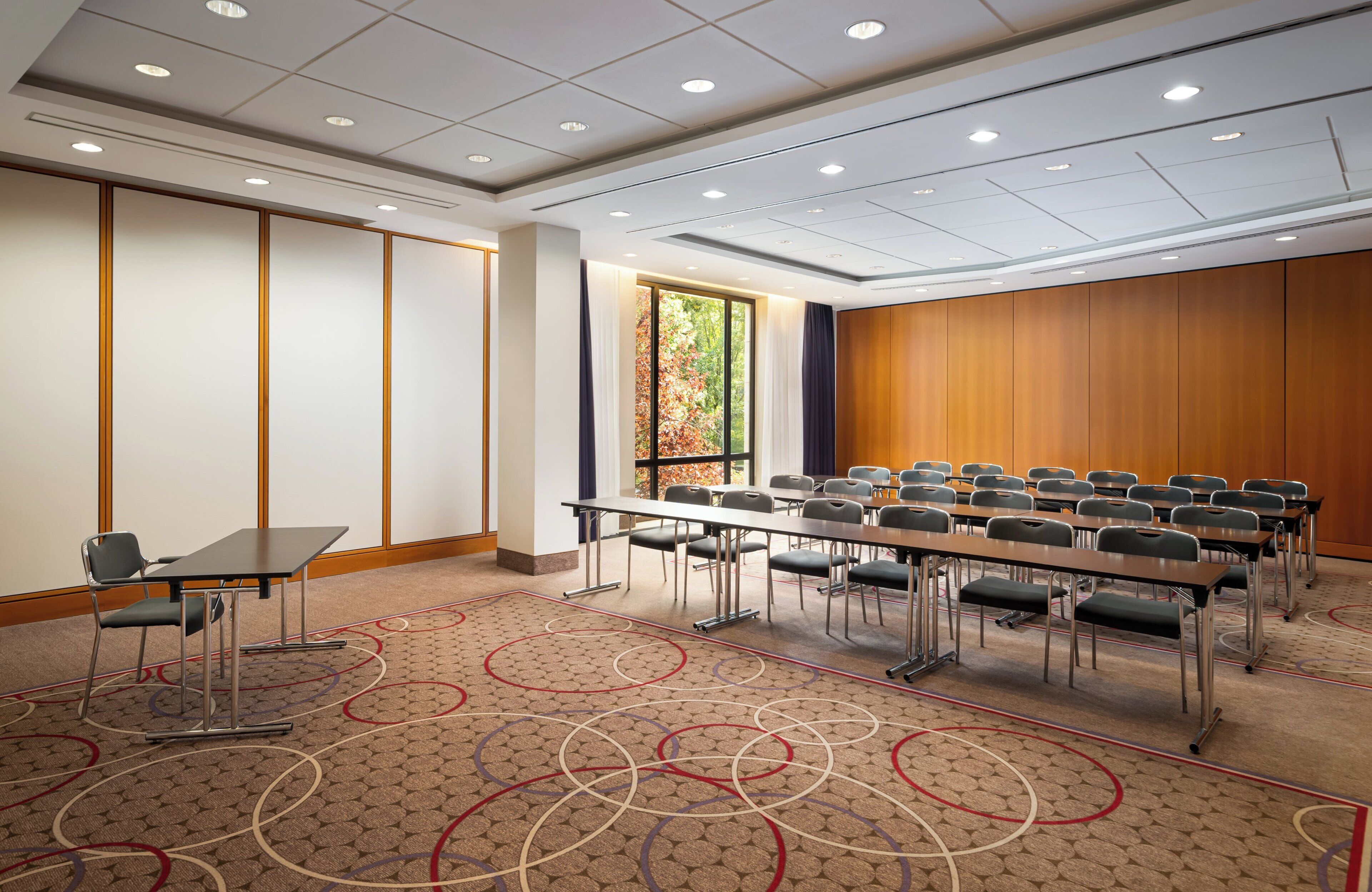 A conference room with a long table, chairs, and a carpeted floor.