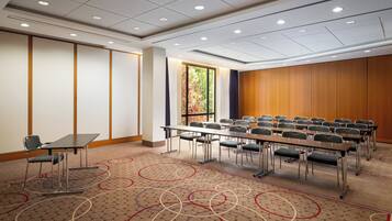 Una sala de conferencias con una mesa larga, sillas y piso alfombrado.
