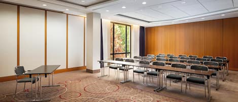 Una sala de conferencias con una mesa larga, sillas y piso alfombrado.
