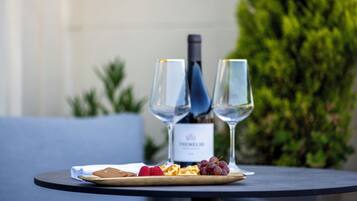 Une table avec une bouteille de vin, deux verres et une assiette de nourriture.