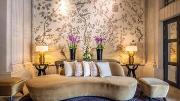 Una habitación con un sofá curvo, dos lámparas y un papel tapiz floral.