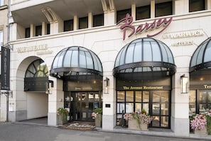 Um hotel com fachada moderna, amplas janelas de vidro e uma placa chamativa com o nome 'Barsey'.