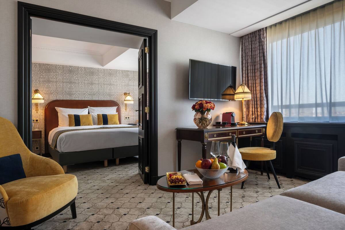 A hotel room with a bed, a desk, a chair, a TV, and a window with curtains.