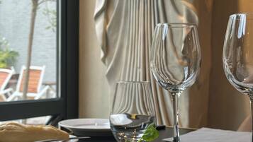 Une table à manger avec une assiette de nourriture, deux verres à vin et un rideau décoratif en arrière-plan.