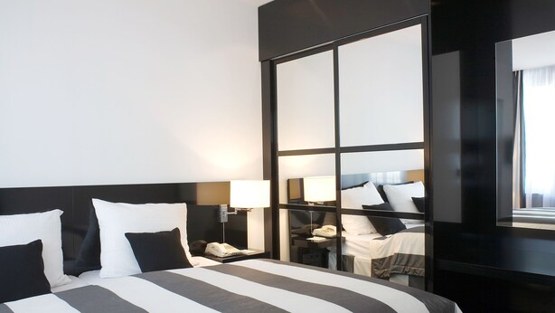 Habitación de hotel con una cama grande, lámparas de noche, una mesita de noche y un espejo.