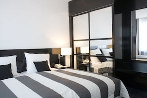 Habitación de hotel con una cama grande, lámparas de noche, una mesita de noche y un espejo.