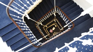 Una escalera caracol con un espacio abierto en el centro, rodeada de escalones azules con diseños blancos.