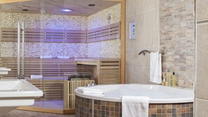Un bagno moderno con una vasca freestanding, un angolo doccia in vetro e un pavimento in legno.