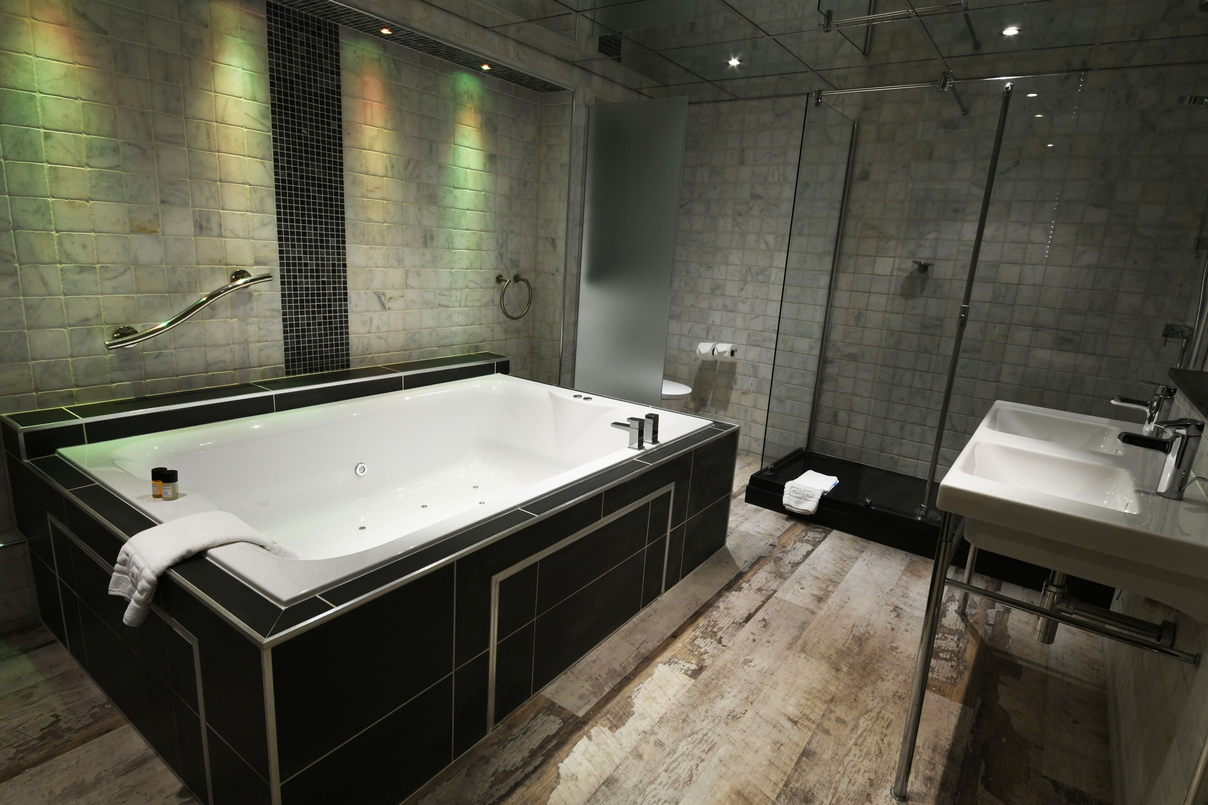 Ein modernes Badezimmer mit einer großen Badewanne, einem separaten Waschbecken und einer Duschkabine.