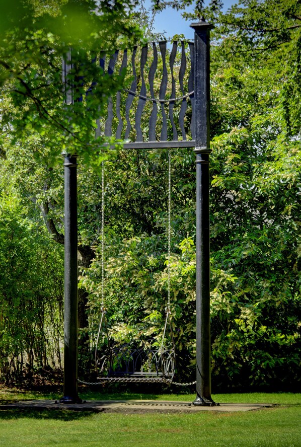 A swing set with a metal frame and chains, surrounded by lush greenery and trees. - Best Western Premier Doncaster Mount Pleasant Hotel (Doncaster)