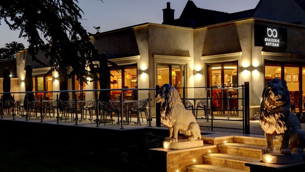 Un ristorante con posti a sedere all'aperto e due statue di leoni.