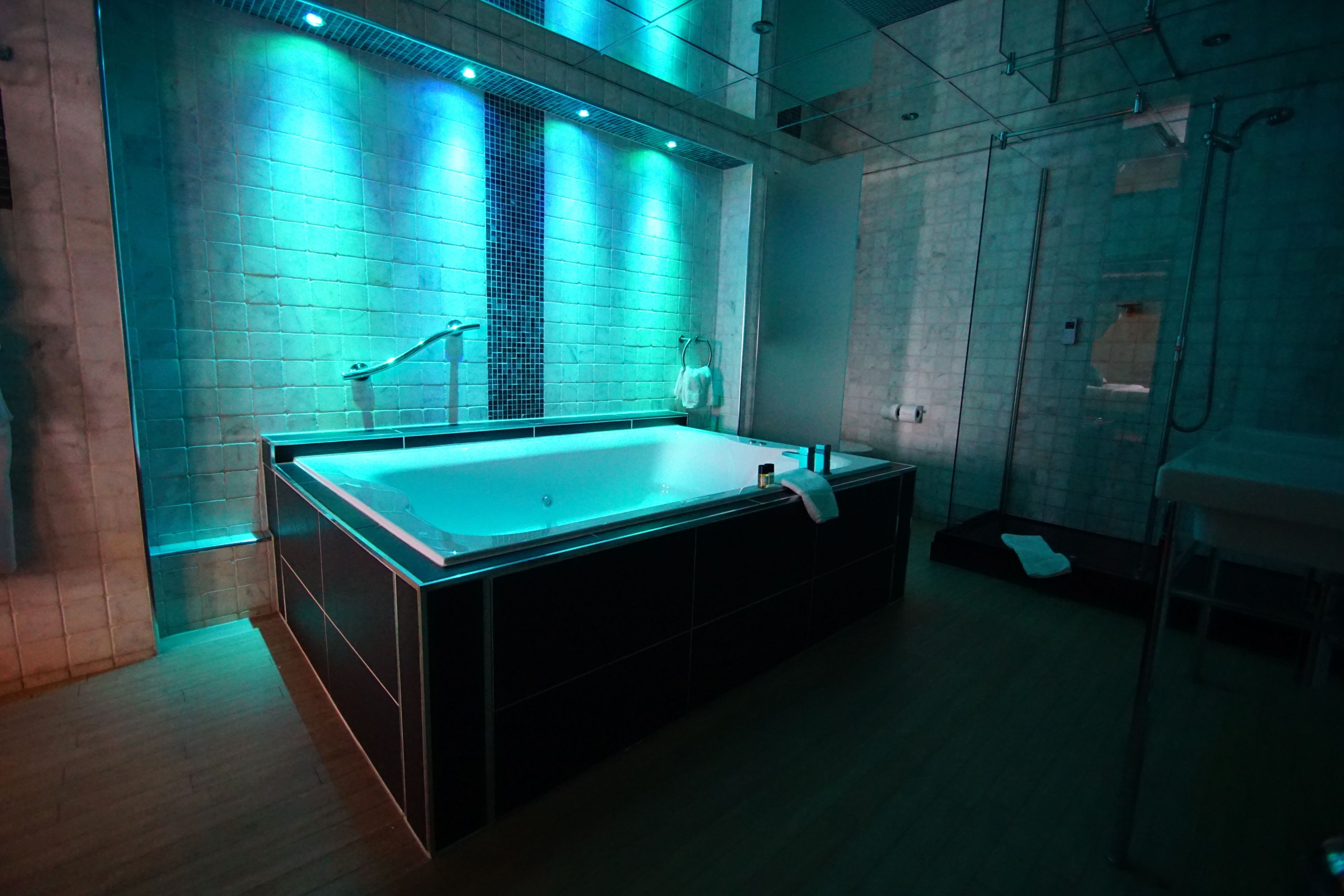 A modern bathroom with a large bathtub, a towel rack, and a shower area.