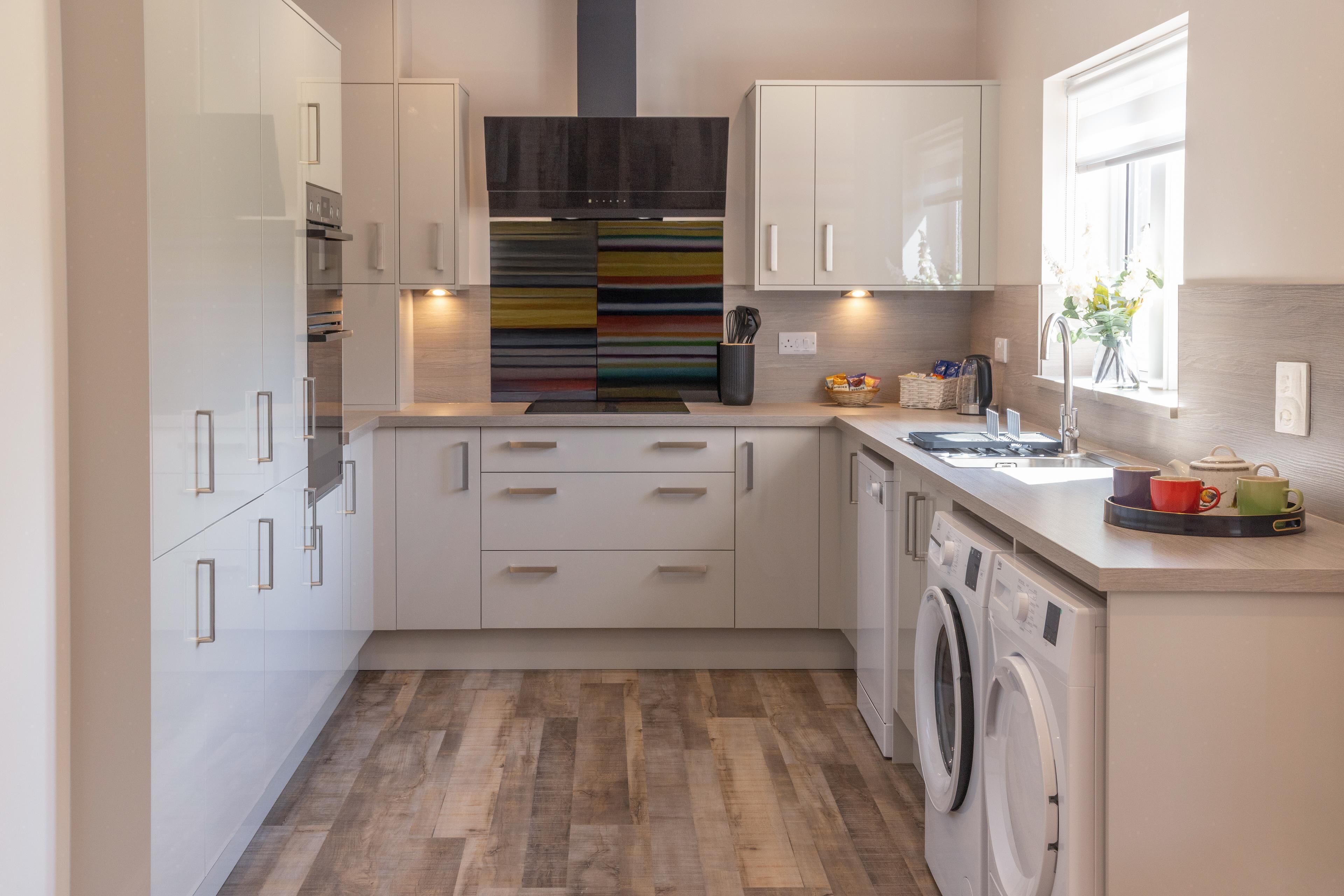 A compact kitchen with a washing machine, a sink, and a window with a view.