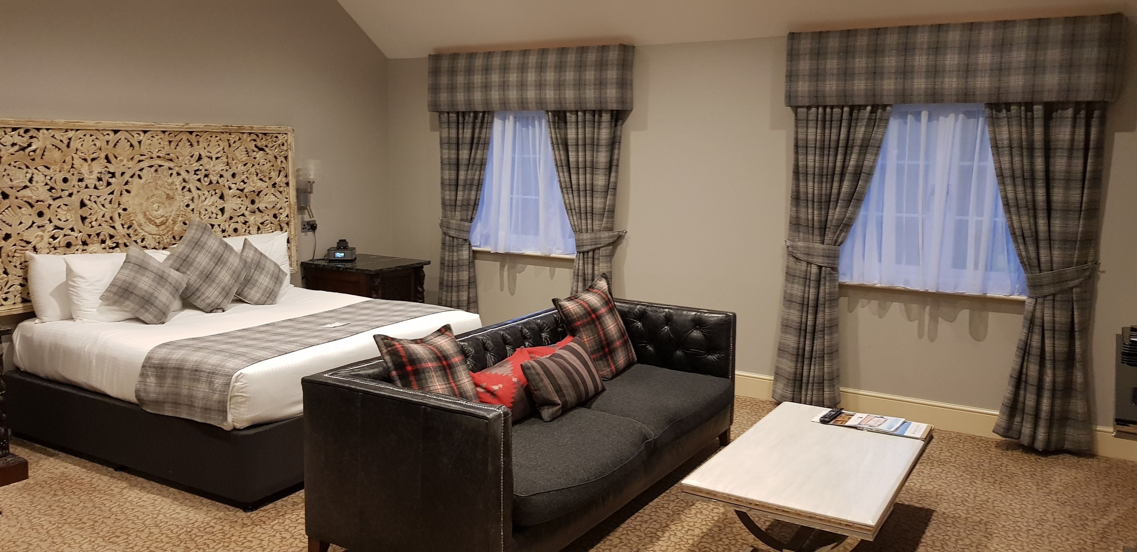 Una habitación de hotel con cama, sofá, mesa de centro y cortinas.