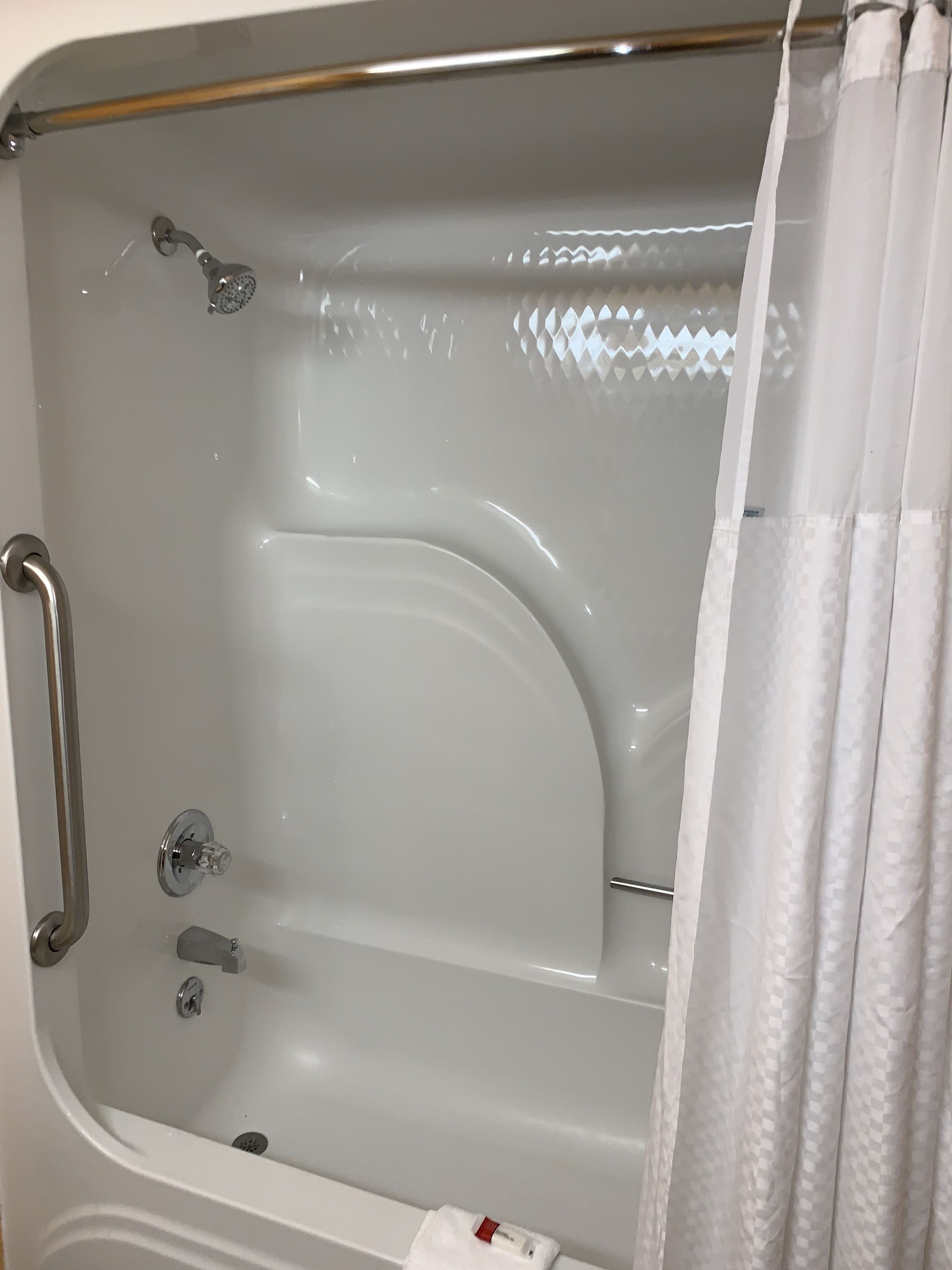A bathtub with a showerhead, grab bar, and a towel rack.