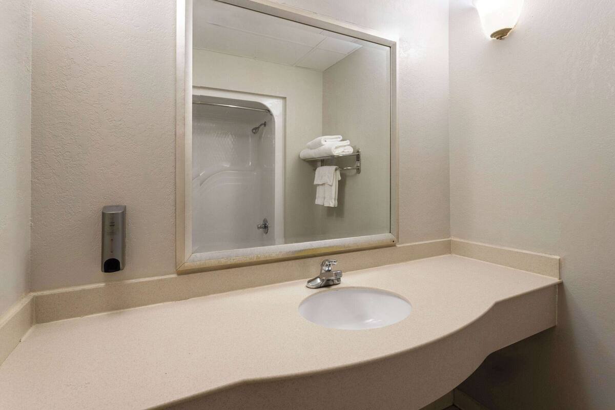 Un baño con lavamanos, espejo y perchero para toallas.