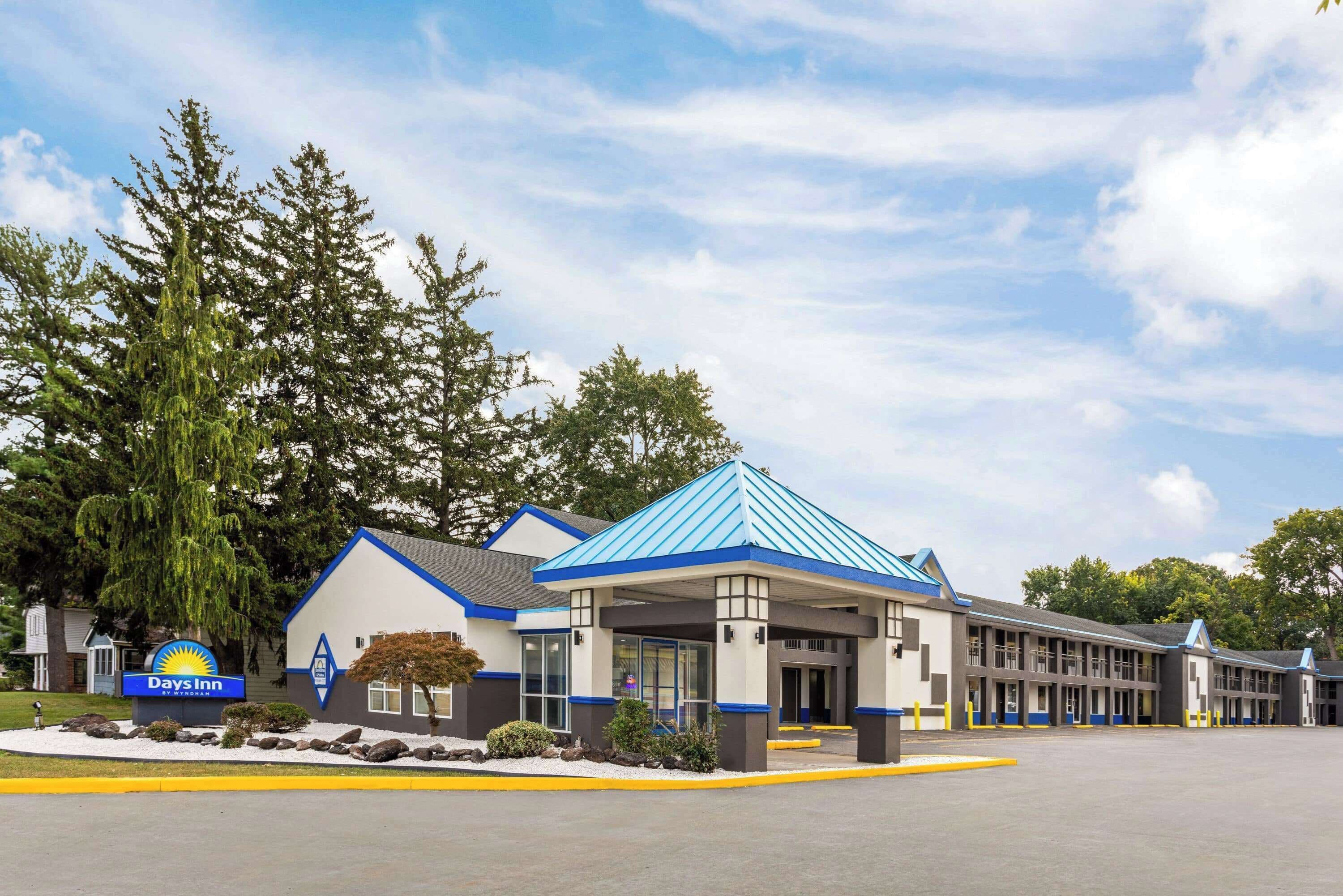 A Days Inn with a blue roof, a covered parking area, and a signboard.