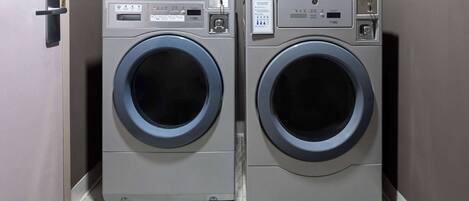 Two front-loading washing machines in a laundry room with a door on the left.