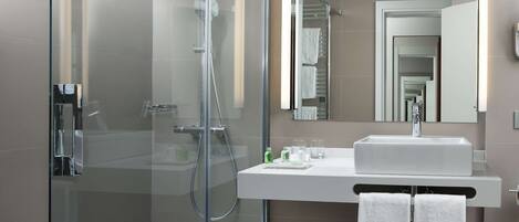A modern bathroom with a glass-enclosed shower, a white sink, and a mirror above it.
