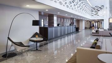 A modern lobby with a reception desk, seating area, and a unique ceiling design.