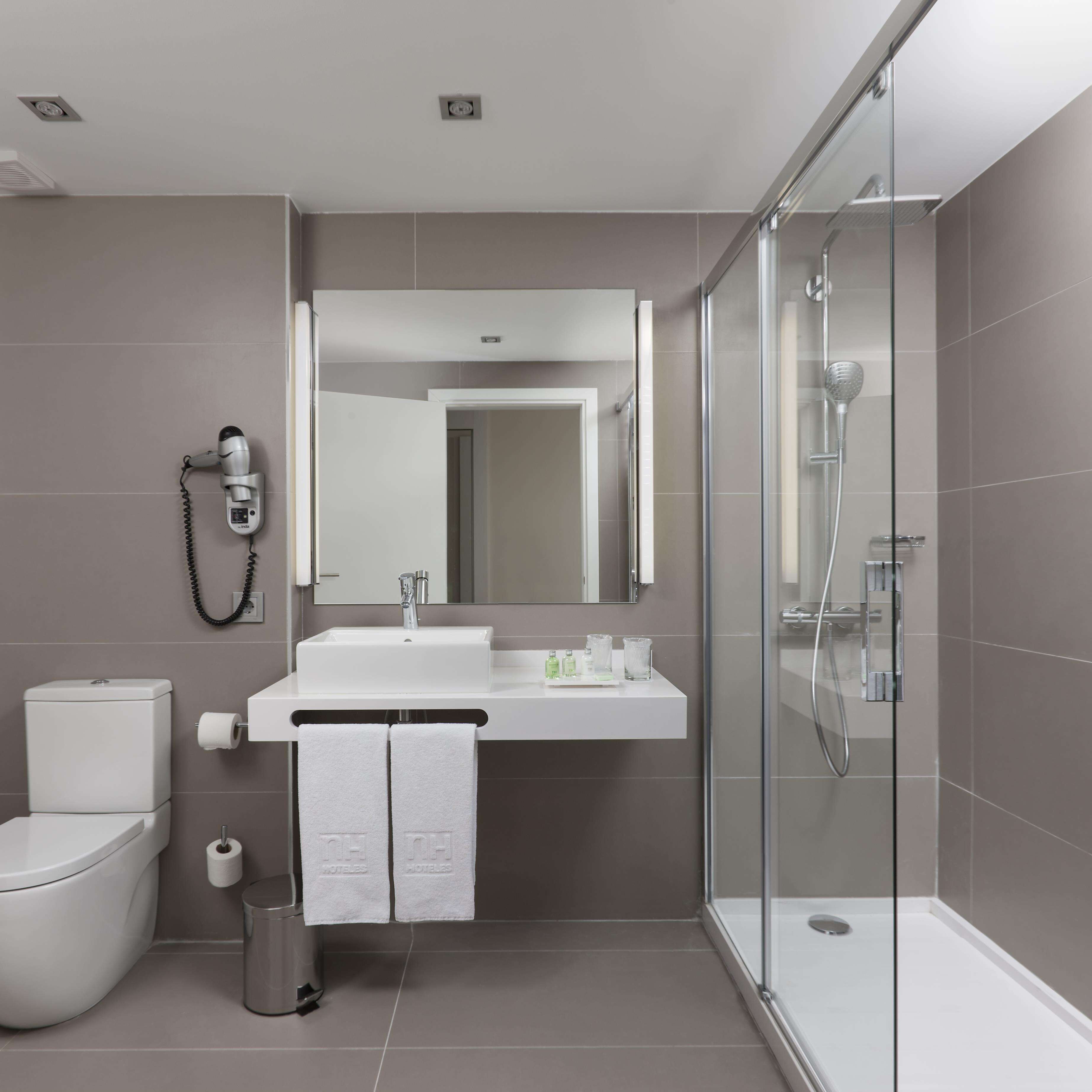 A modern bathroom with a glass-enclosed shower, a white sink, and a toilet.