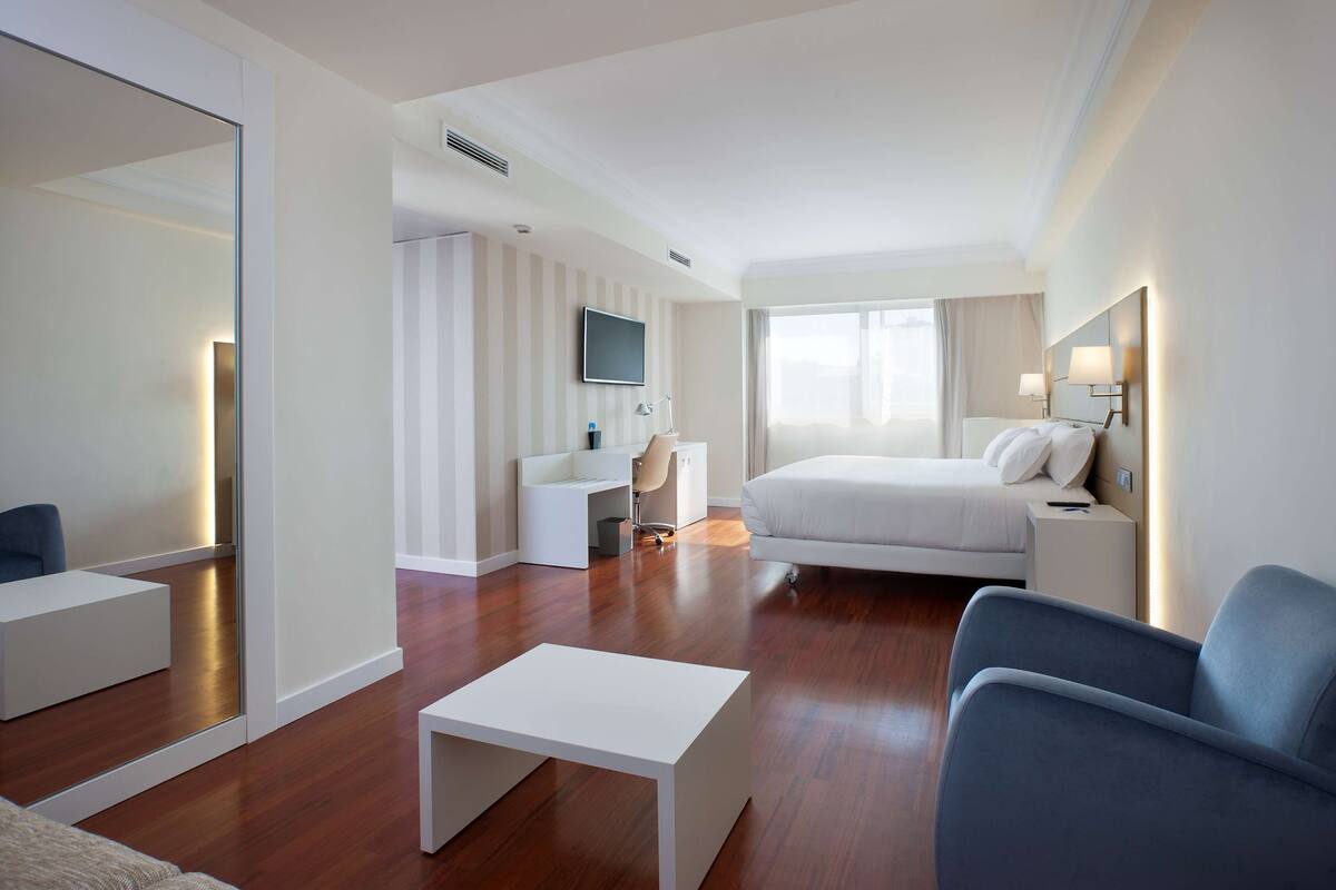 Une chambre d’hôtel moderne équipée d’un lit, d’un bureau, d’une chaise et d’un téléviseur.