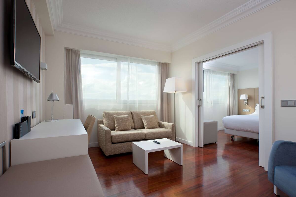 Une chambre d’hôtel équipée d’un canapé, d’une table basse, d’une télévision, d’un lit et d’une chaise.