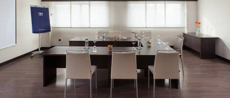 A conference room with a long table, six chairs, and a projector screen.