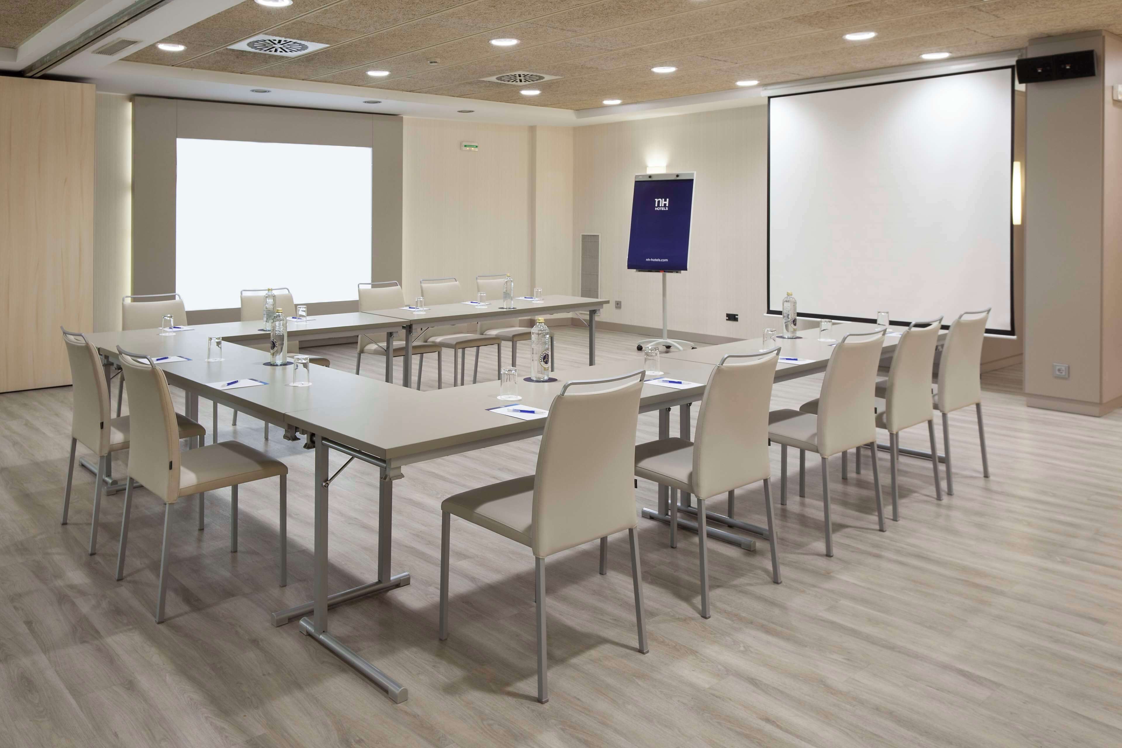 A conference room with a long table, chairs, a projector screen, and a whiteboard.