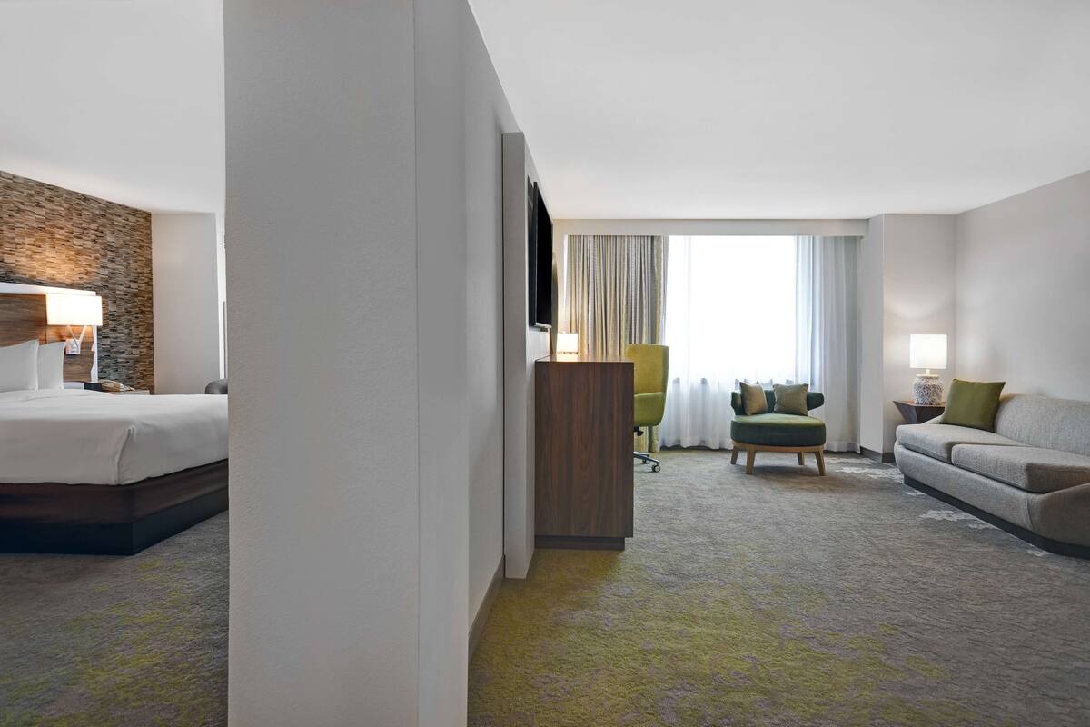 Een hotelkamer met een bed, een bureau, een stoel, een bank en een televisie.