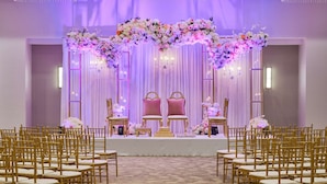 Eine Bühne mit Blumendekoration, zwei Stühlen und einem Hintergrund.