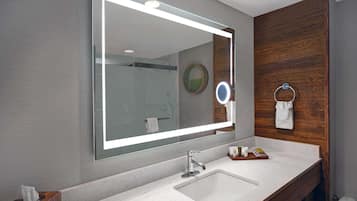 A modern bathroom with a large mirror, two sinks, and a wooden vanity.