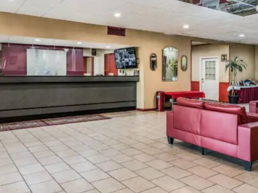 A reception area with a counter, red sofas, and a tiled floor.