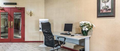 Un espace d’accueil d’hôtel comprenant un comptoir, un ordinateur et un tableau encadré accroché au mur.